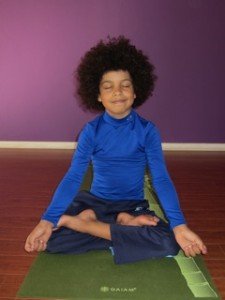kid on yoga mat with eyes closed meditating