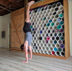 man doing handstand in front yoga mat cubbies