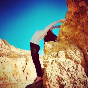 woman doing yoga pose on side of a mountain
