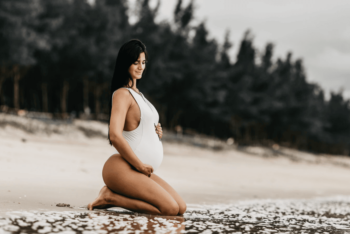 pregnant woman kneeling beach