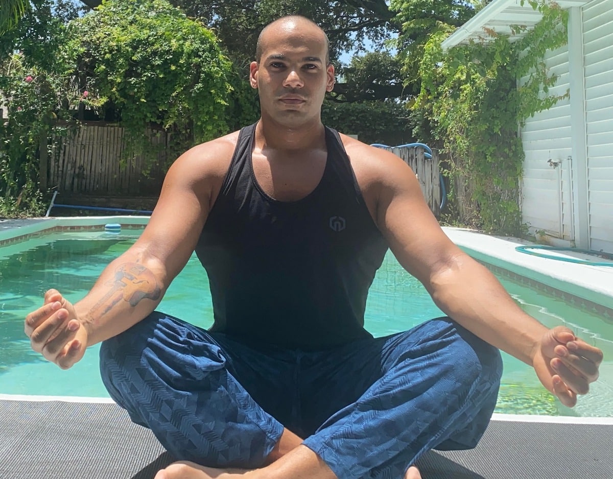 man doing yoga pose in front of pool
