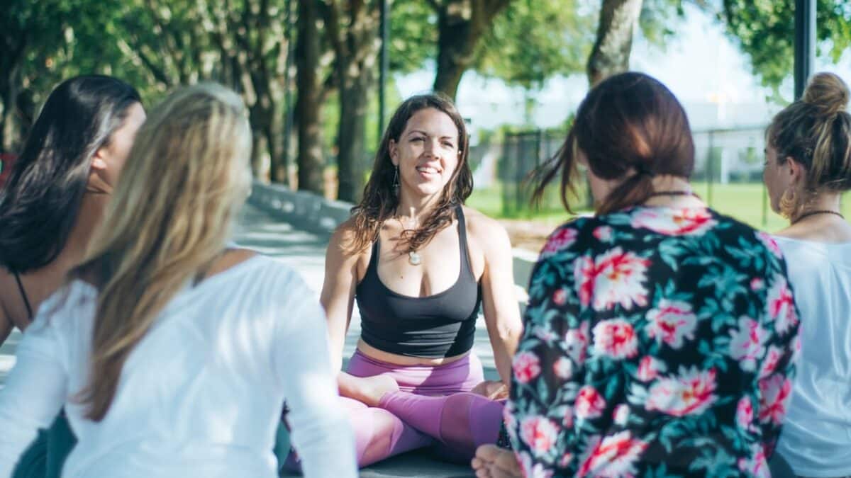 woman sitting in yoga pose surrounded by group of women