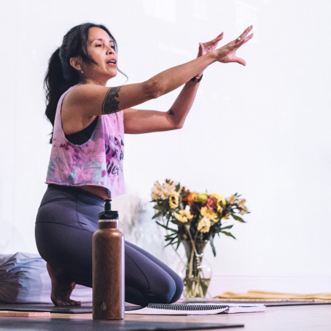 yoga studio instructor kneeling arms stretched